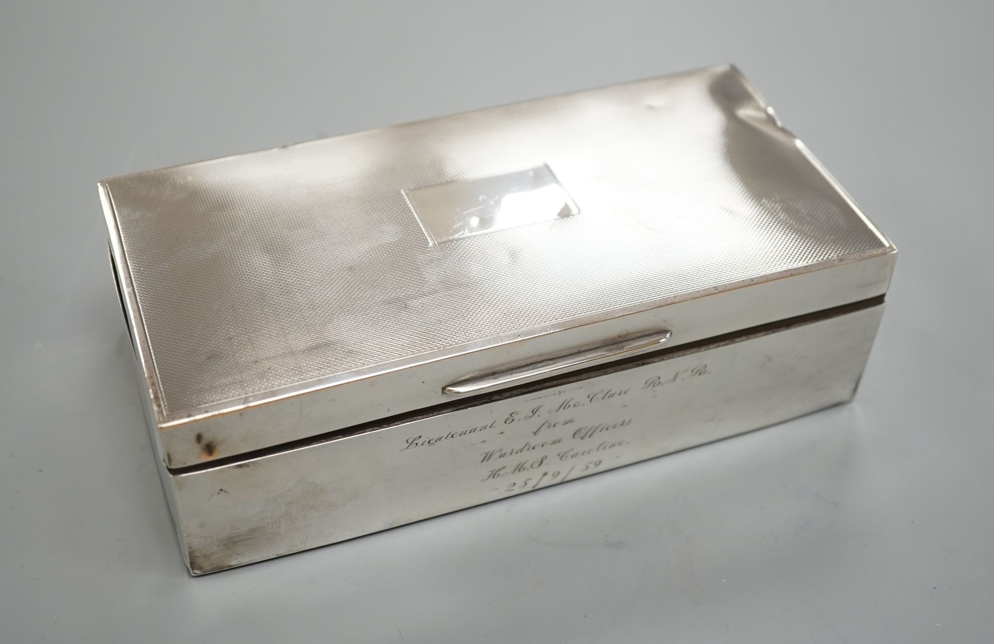 A late 1950's engine turned silver mounted rectangular cigarette box, with engraved inscription, 17.8cm.